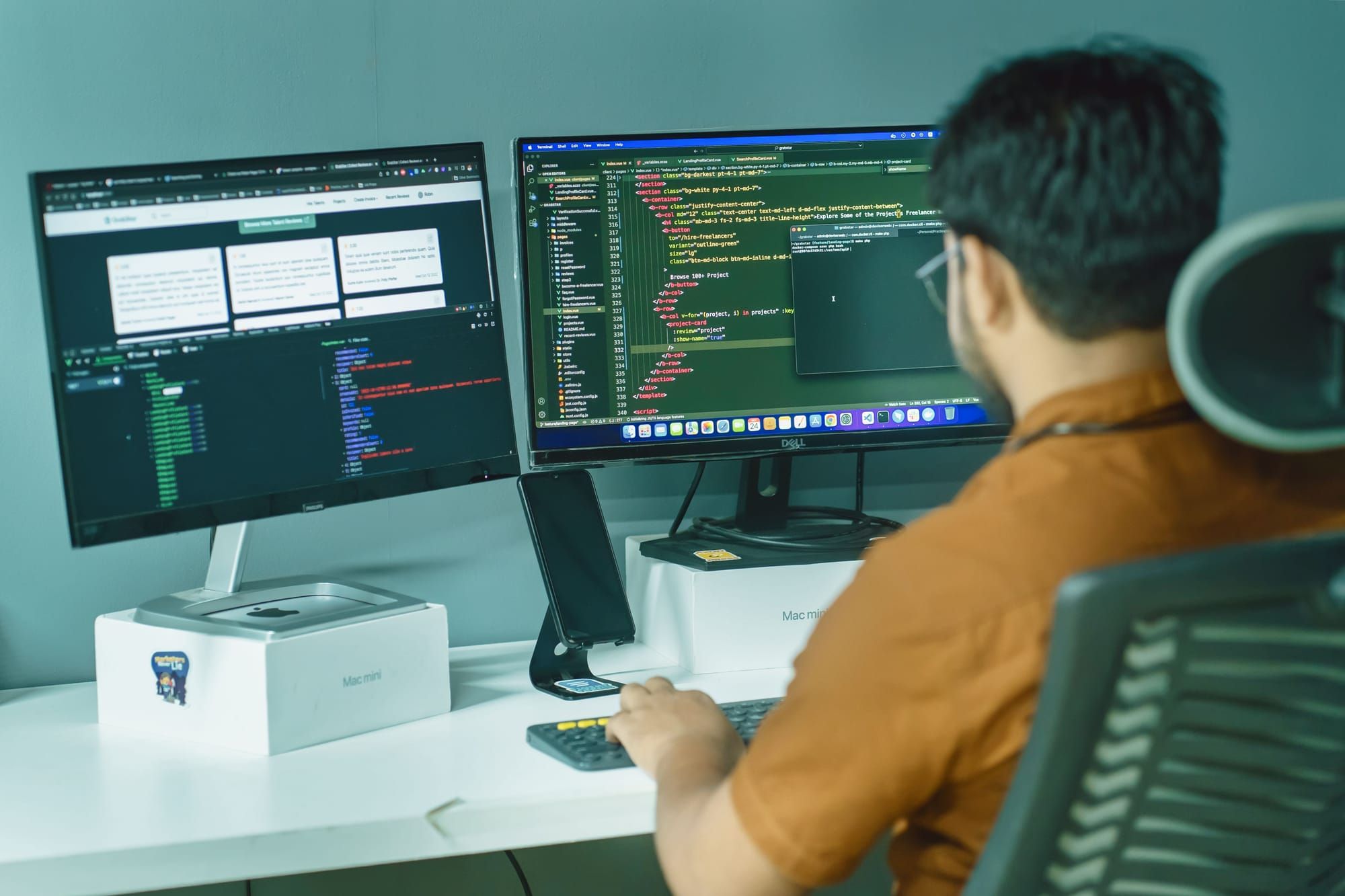 Técnico sentado ante dos monitores con código y una terminal abiertos